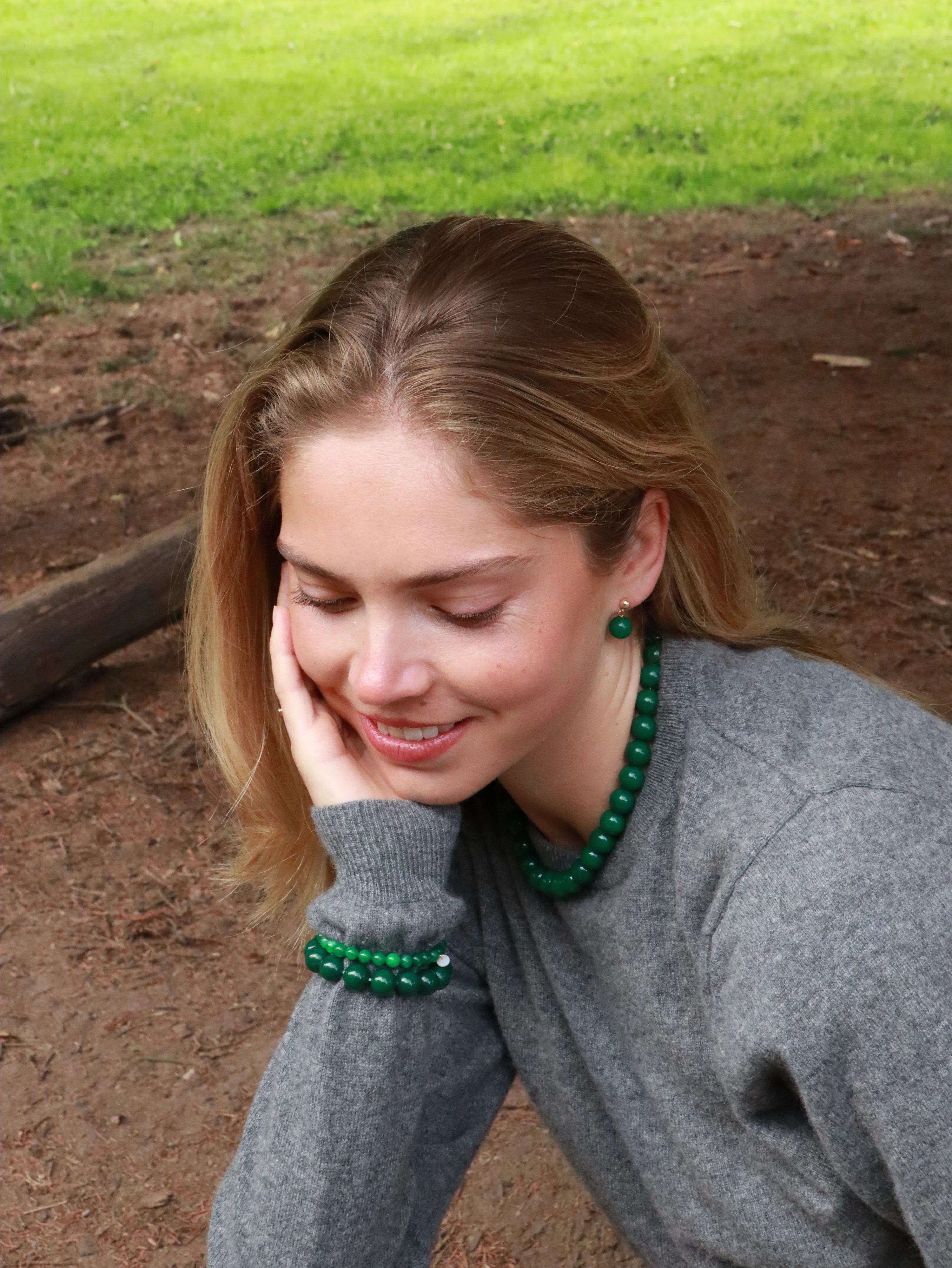 Frau trägt Ohrringe, Kette und Armbänder aus grüner Jade von Soi