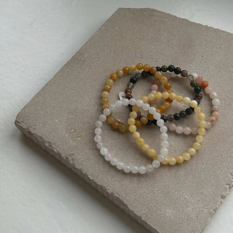 Armbänder von Soi aus Achat, Jade, Aventurin und Mondstein auf Betonfliese