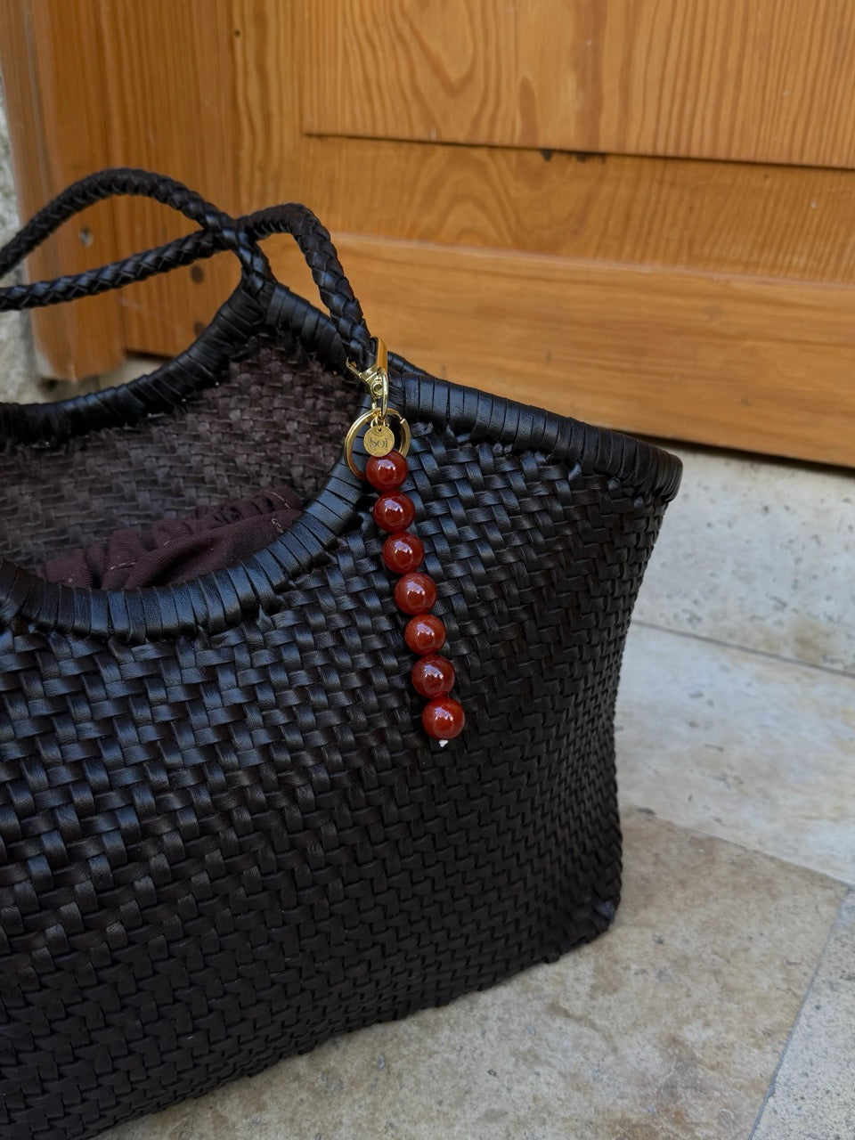 Bag Charm aus roten Jade Perlen an brauner Tasche befestigt