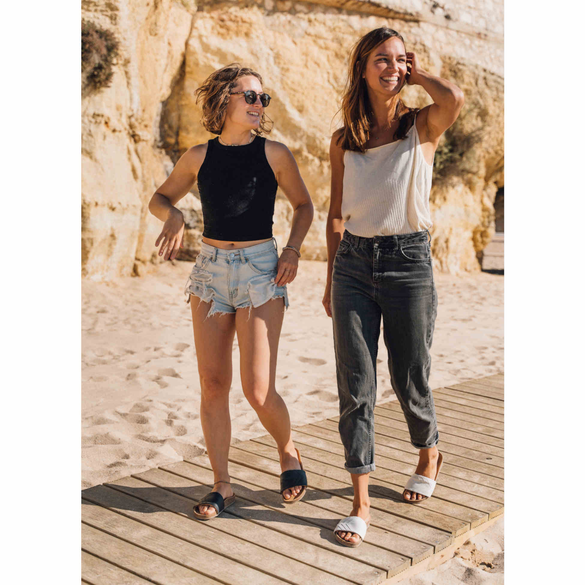 Weiße Sandalen und schwarze Sandalen, Moodbild am Strand, vegan, bequemes Fußbett Marke Fünve, Modell YANG, vielseitige Sandale oder Hausschuh