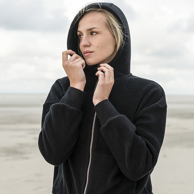 Frau trägt schwarze Fleecejacke aus Bio Baumwolle mit Kapuze