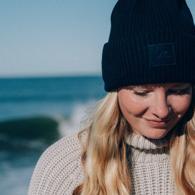 Frau in kuscheliger Mütze am Meer