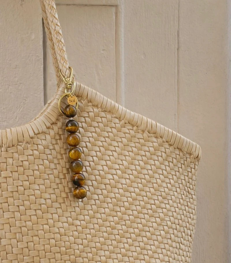 Bag Charm aus Tigerauge Perlen an beiger Tasche befestigt