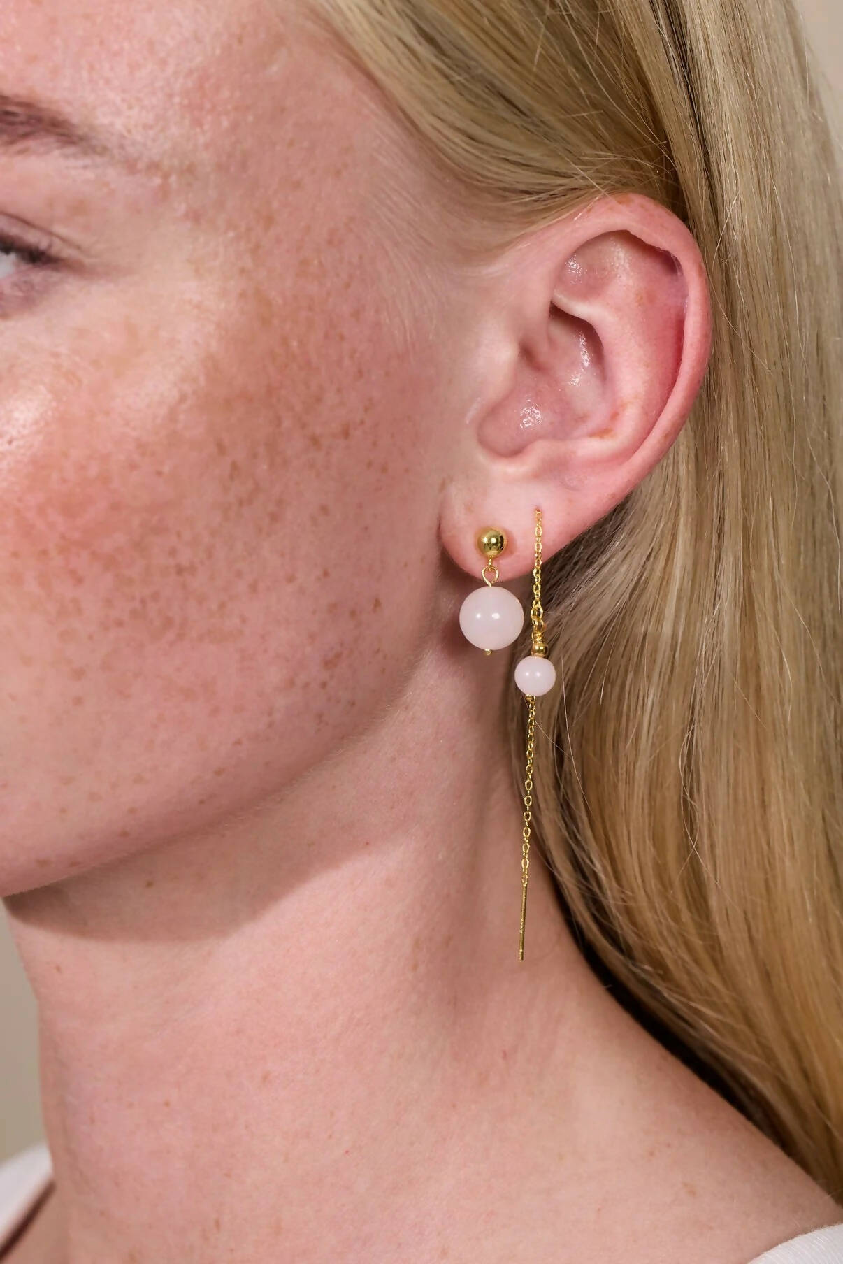 blonde Frau trägt Ohrringe in gold mit rosa Jade Perlen